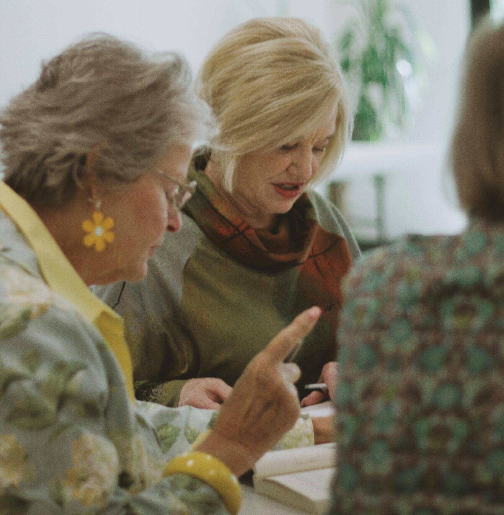 A group of women engages in a bible study in a welcoming interior space.